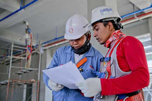 Two construction workers going over plans for a construction job.