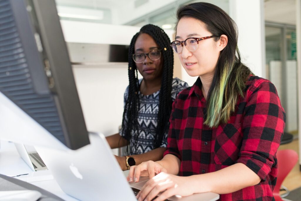 Two people on computers doing website management.